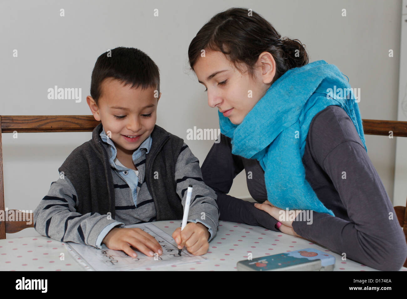 6-year-old boy writing with his sister Stock Photo