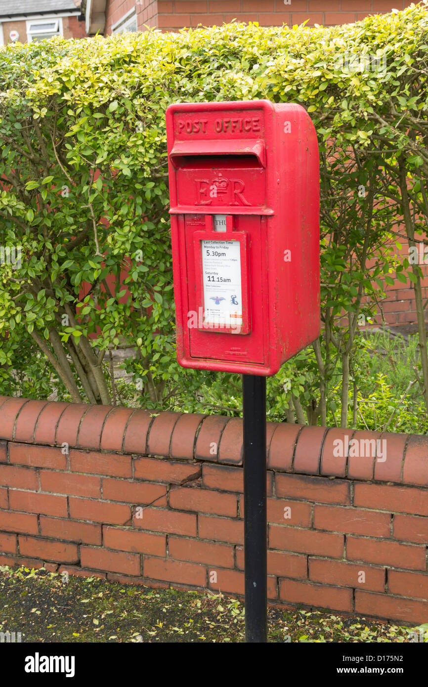 Small standalone post box mounted on a steel post on a street in the suburbs of Bolton. Stock Photo