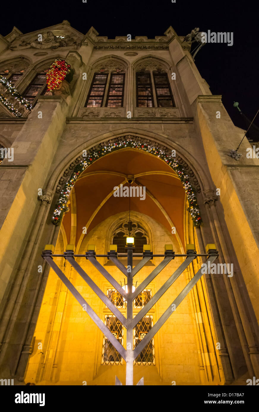 The Hanukkah candelabrum stands with the first candle lit in front of