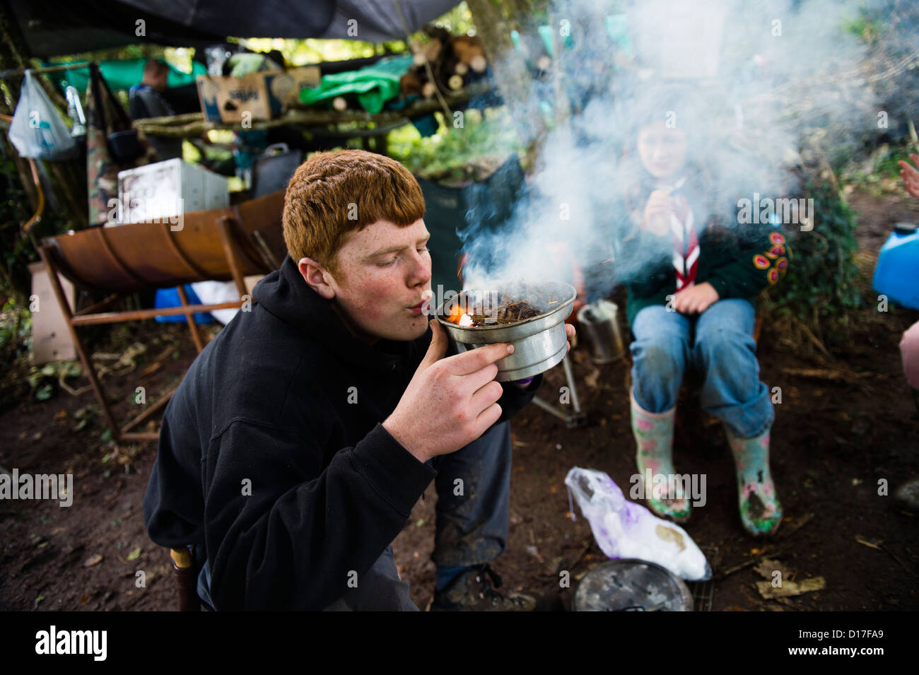 A boy making fire: Scouts learning bushcraft at a camp in Ceredigion, West Wales, UK Stock Photo