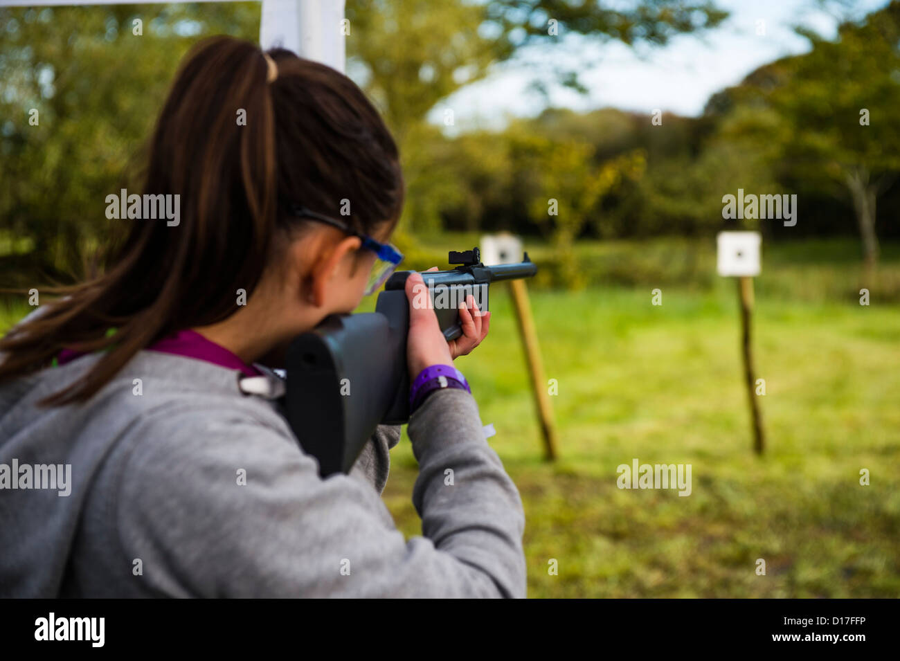 Taking aim at the target: A girl Scout holding  gun learning how to shoot at a target  at a camp in Ceredigion, West Wales, UK Stock Photo