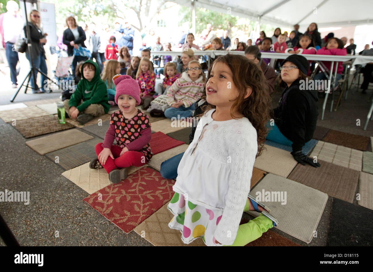 Smiling and happy children sit on carpet mats while listening to children's book author during the Texas Book Festival in Austin Stock Photo
