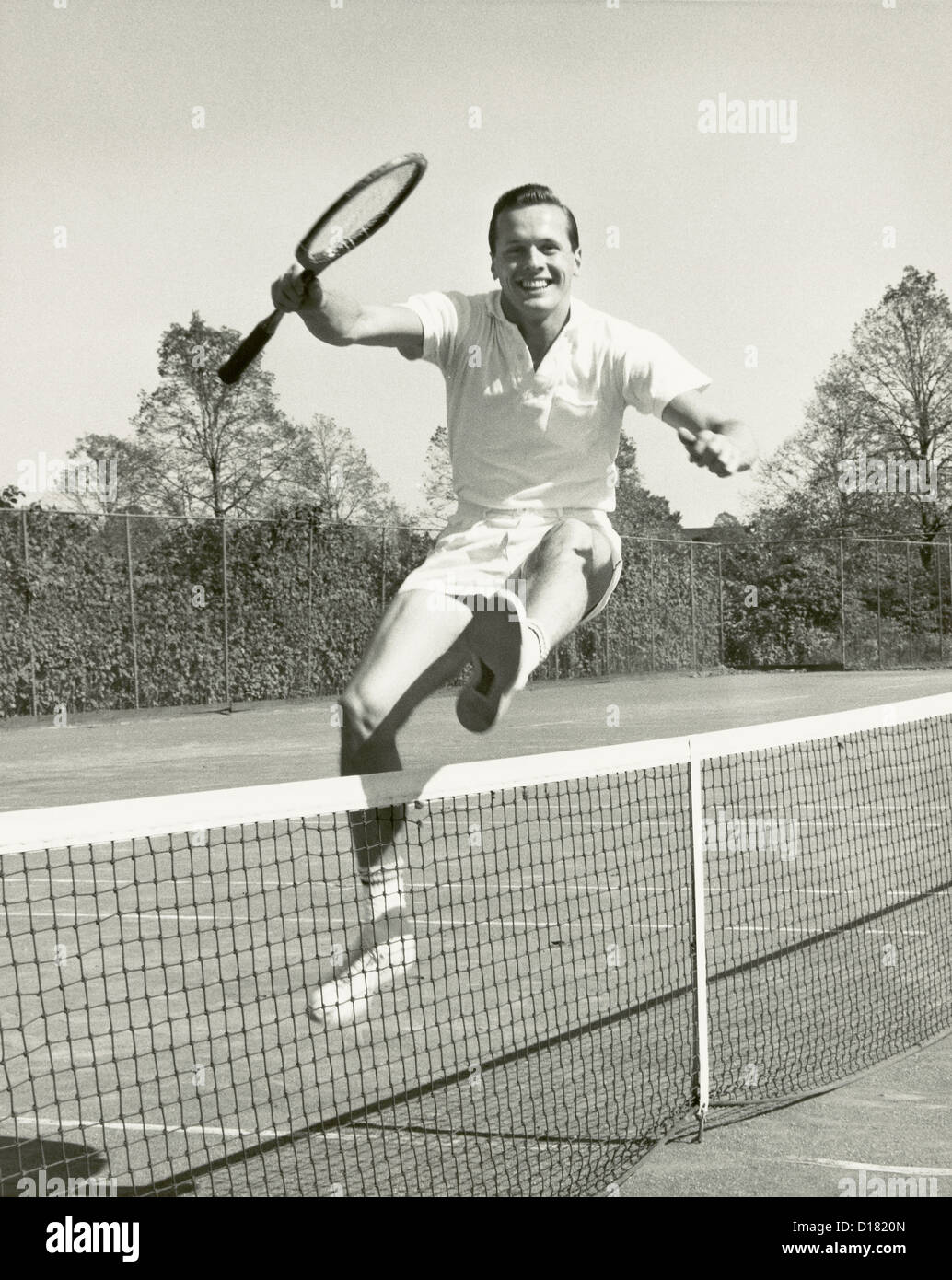 Man holding tennis racquet leaping over tennis net, 1950-1960's Stock Photo  - Alamy