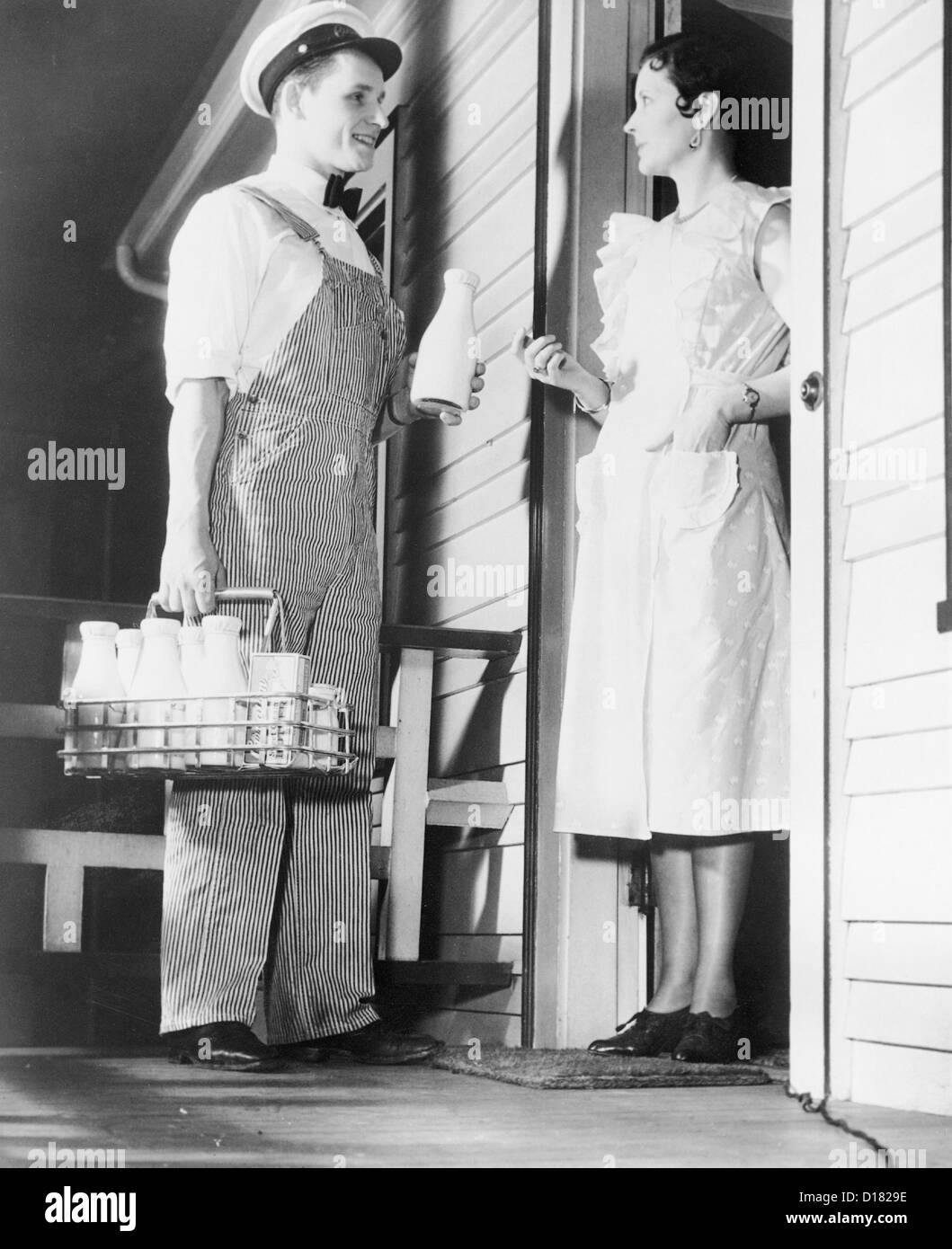 Historic shot of milk man delivering milk to housewife Stock Photo - Alamy