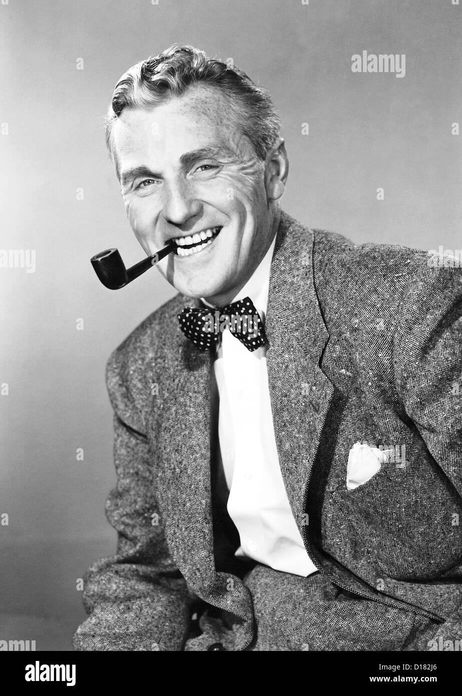 Mature man with bow tie smoking pipe Stock Photo