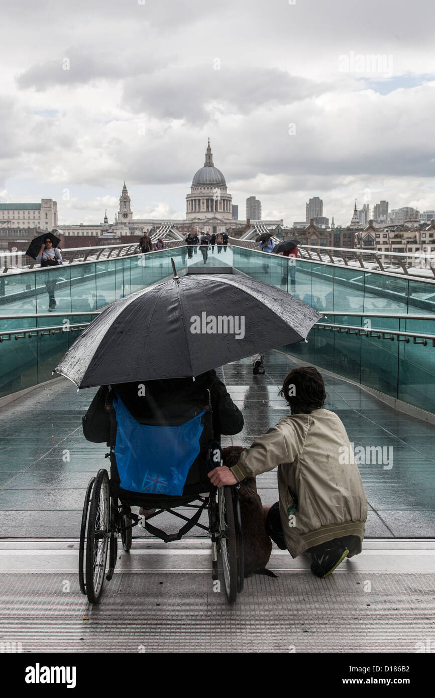 homeless man in wheelchair sitting in the rain with friend on