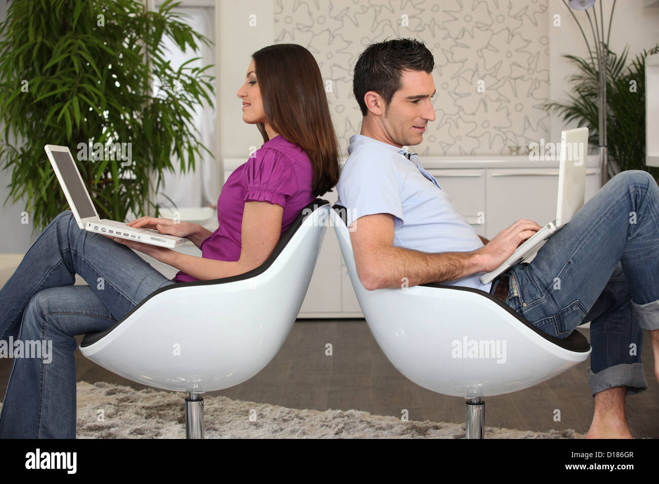 Man and woman sitting back to back using computers Stock Photo Alamy