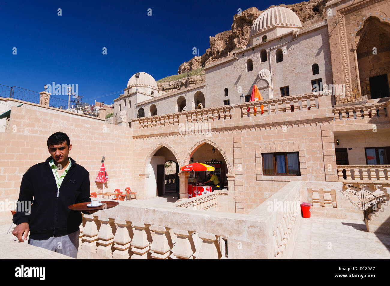 Waiter at the terrace of a cafe inside the historic post office building next to Sultan Isa Medresesi in Mardin, Southeast Turkey Stock Photo