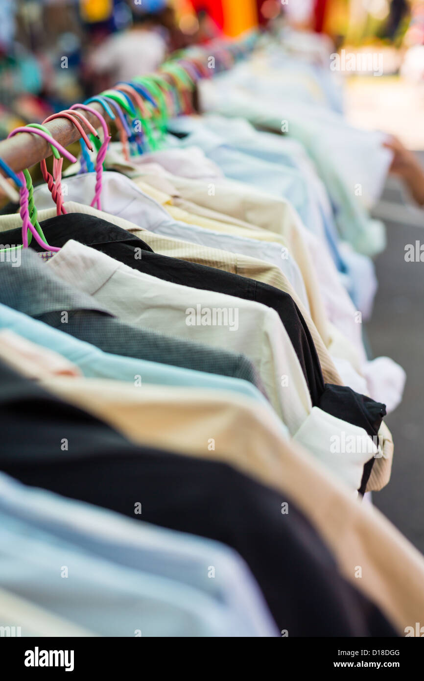 Old shirt hanging on plastic hangers in second hand market Stock Photo