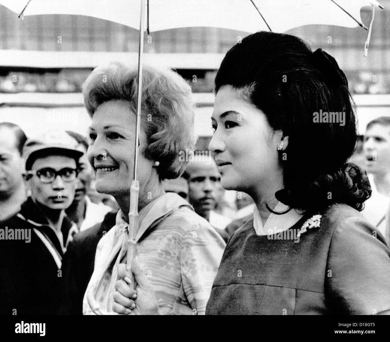 First Lady Pat Nixon (left) and Imelda Marcos stand under an umbrella at Manila airport. President Nixon conferred with Stock Photo