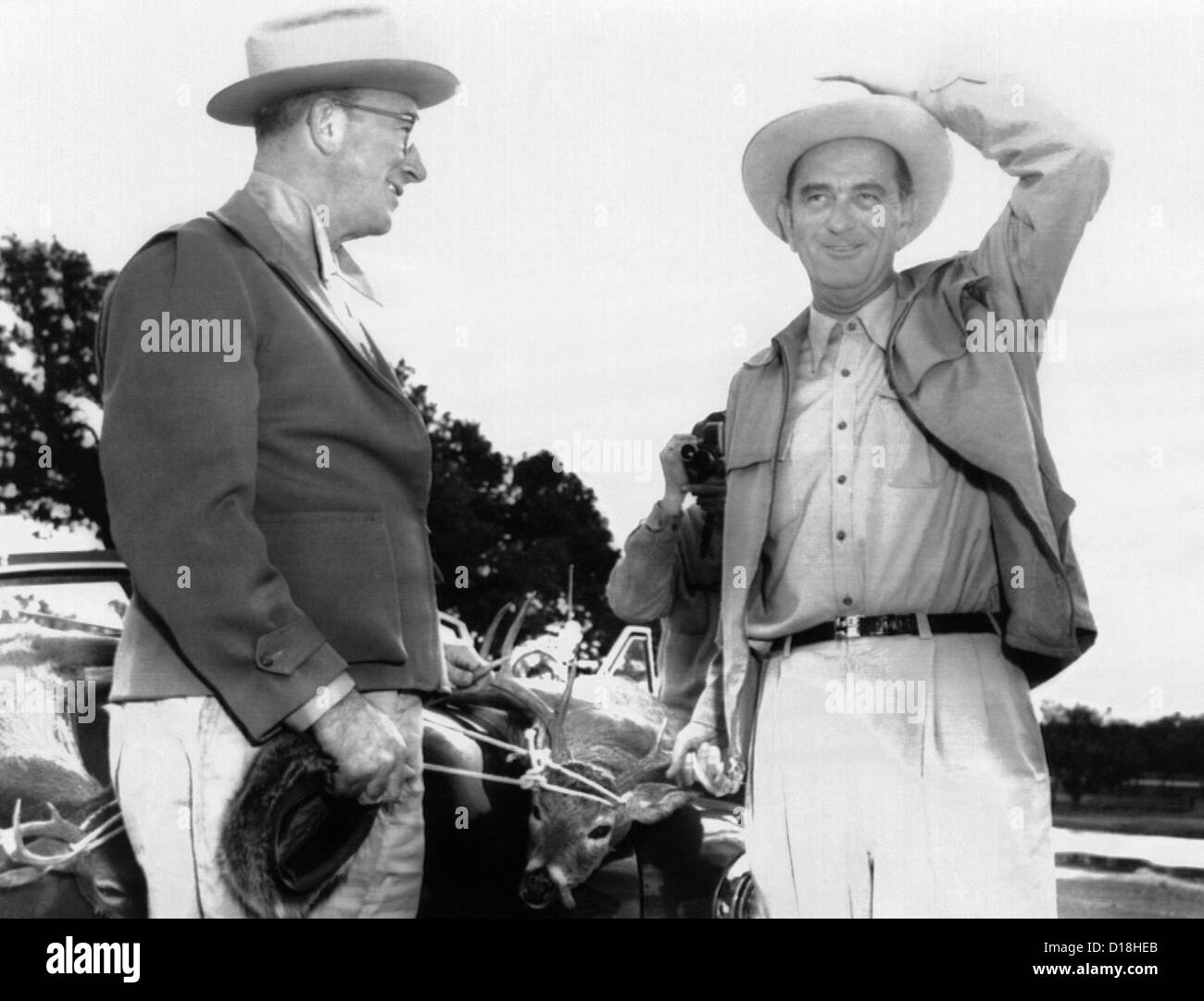 President Lyndon Johnson entertains Senator Estes Kefauver at the LBJ Ranch. There are two dead deer tied to the car behind Stock Photo