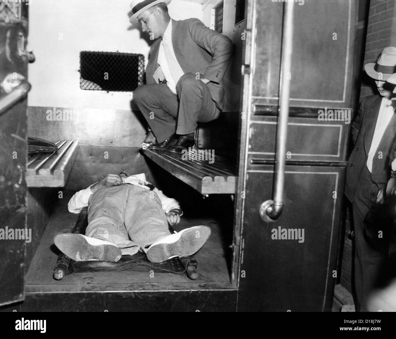 John Dillinger, dead with toes up in a police patrol wagon, is taken from the scene of his killing by FBI agents in Chicago. Stock Photo