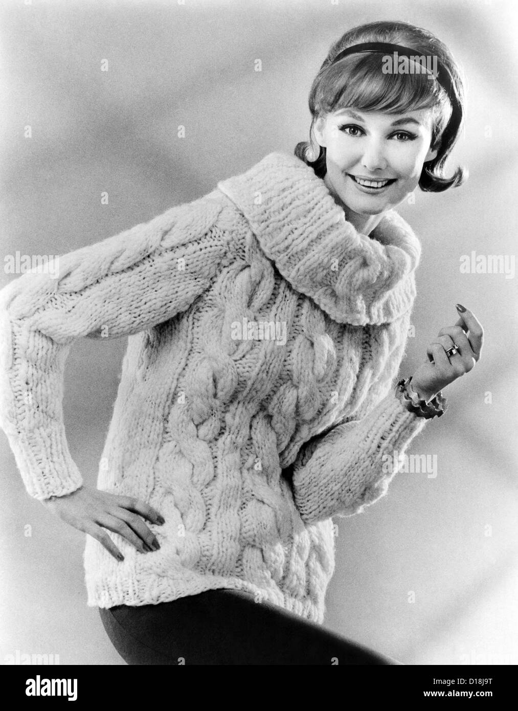 Sweater with a large cowl neck. The model's hair style has bangs, discreet bouffant, and flipped up ends. 1950s defining eye Stock Photo