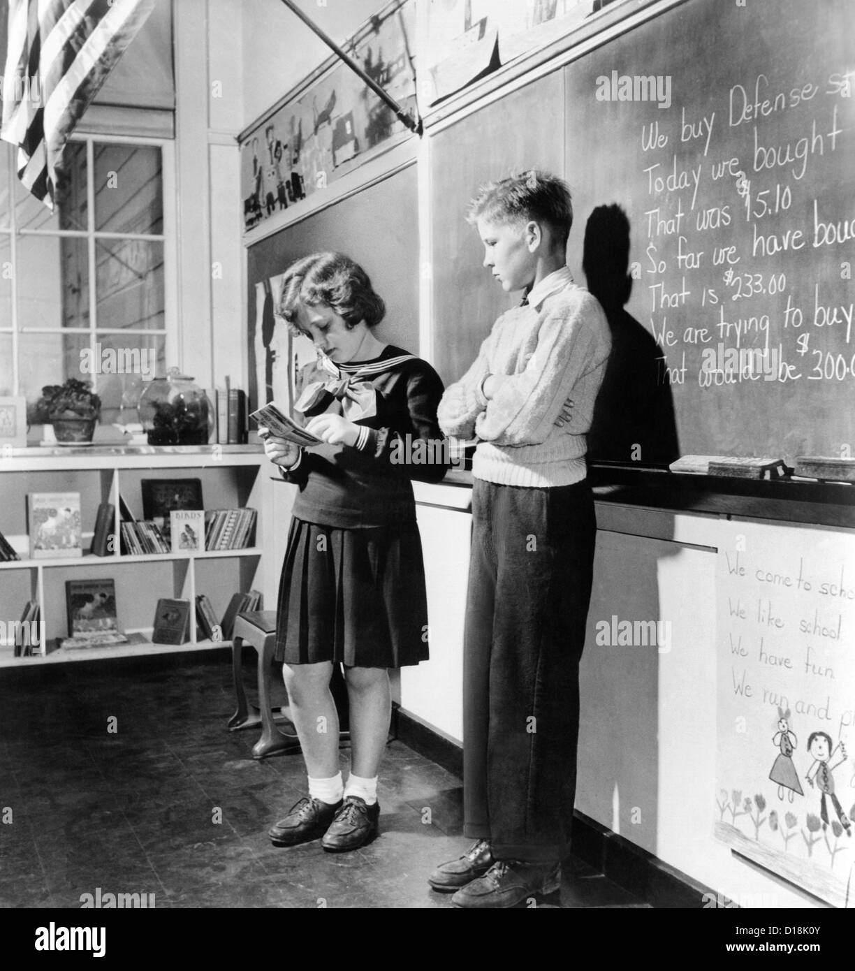 Children's school clothing in 1943. In front of the class under the American flags, they do their arithmetic lesson calculating Stock Photo