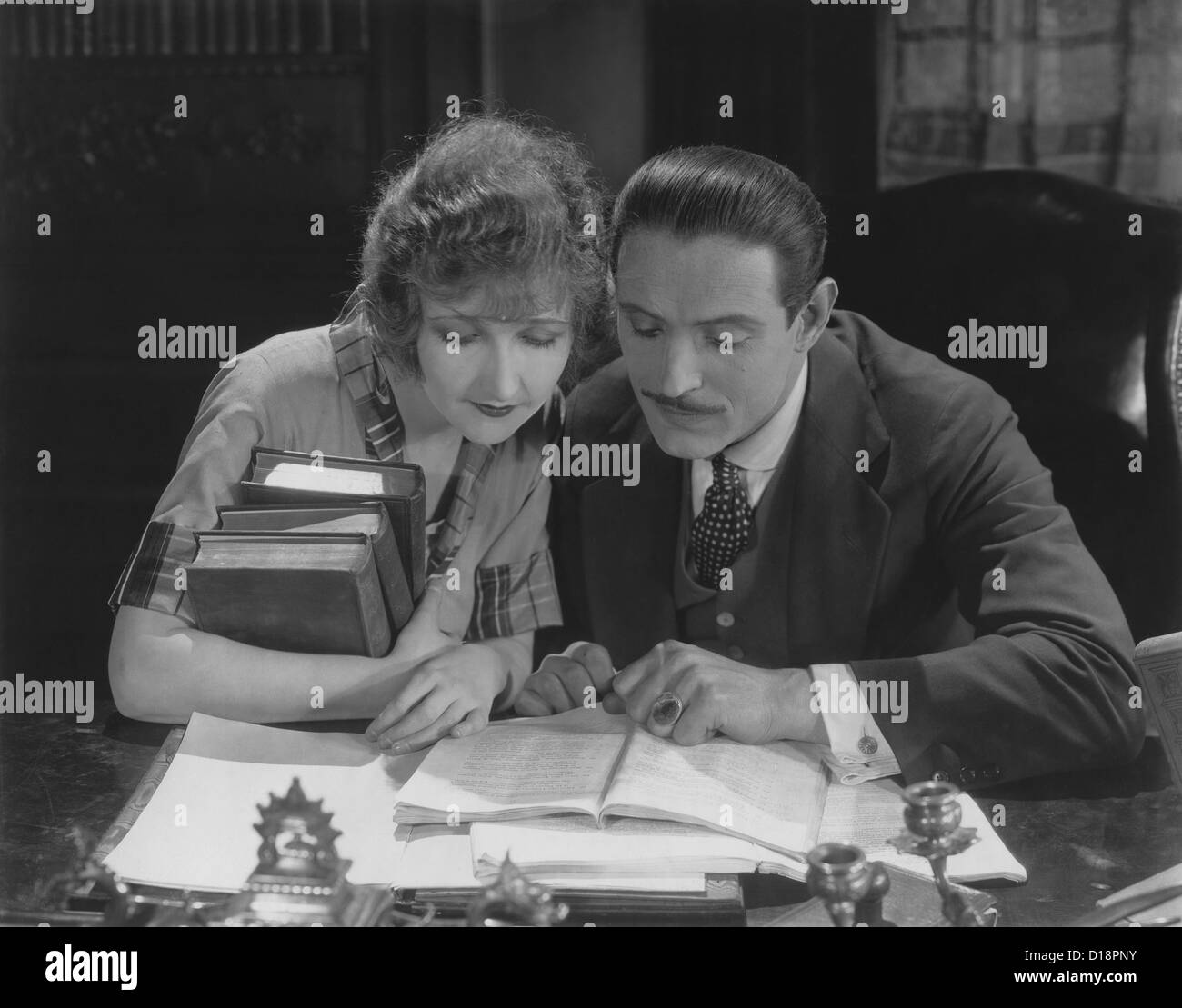 Couple reading book at desk Stock Photo