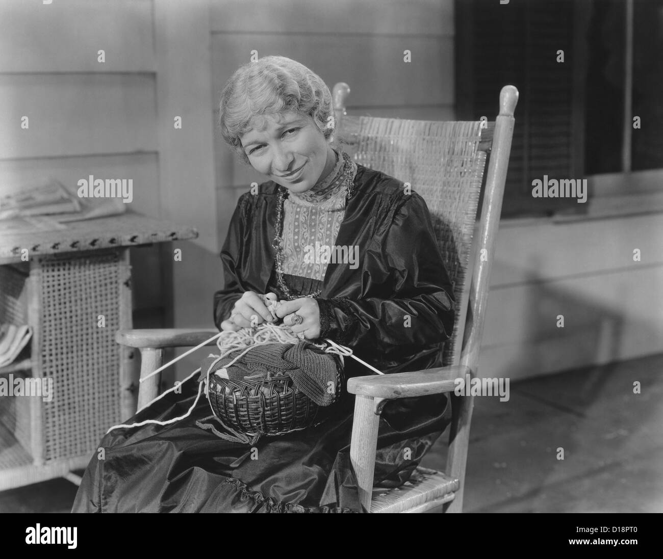 Smiling woman knitting in her rocking chair Stock Photo