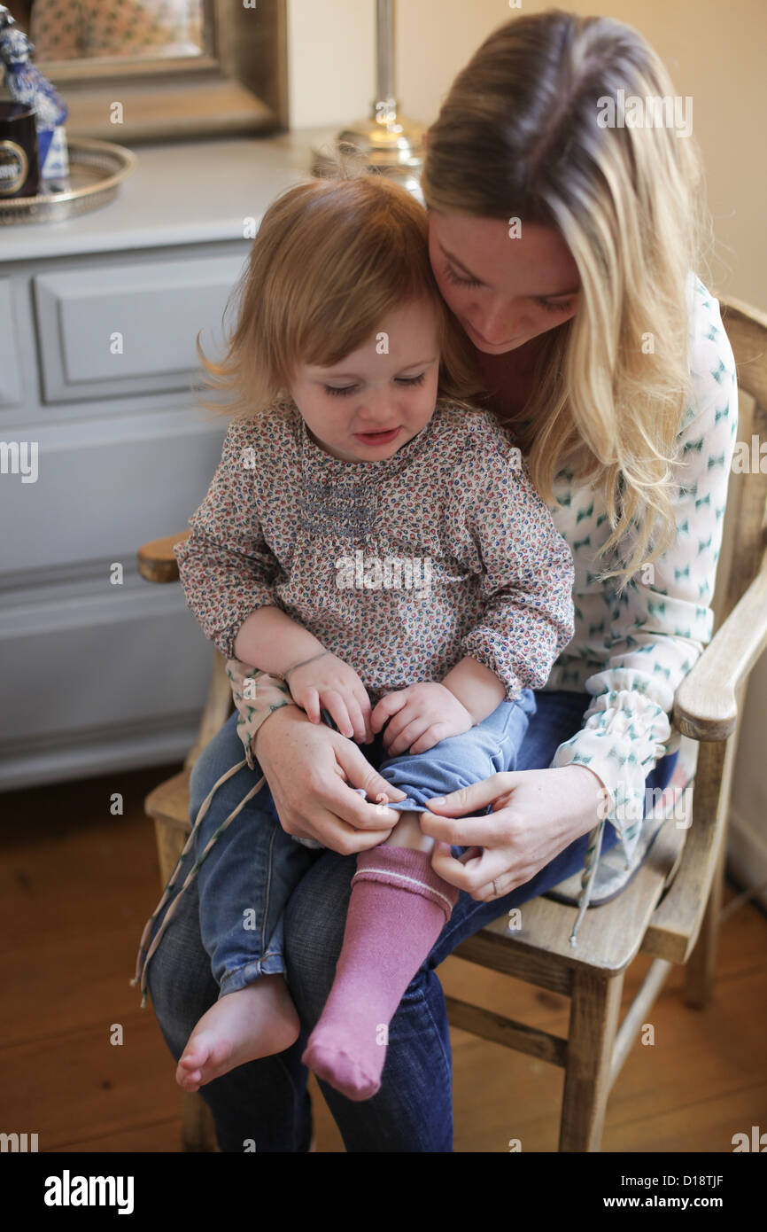 Mother helping daughter put on socks Stock Photo Alamy