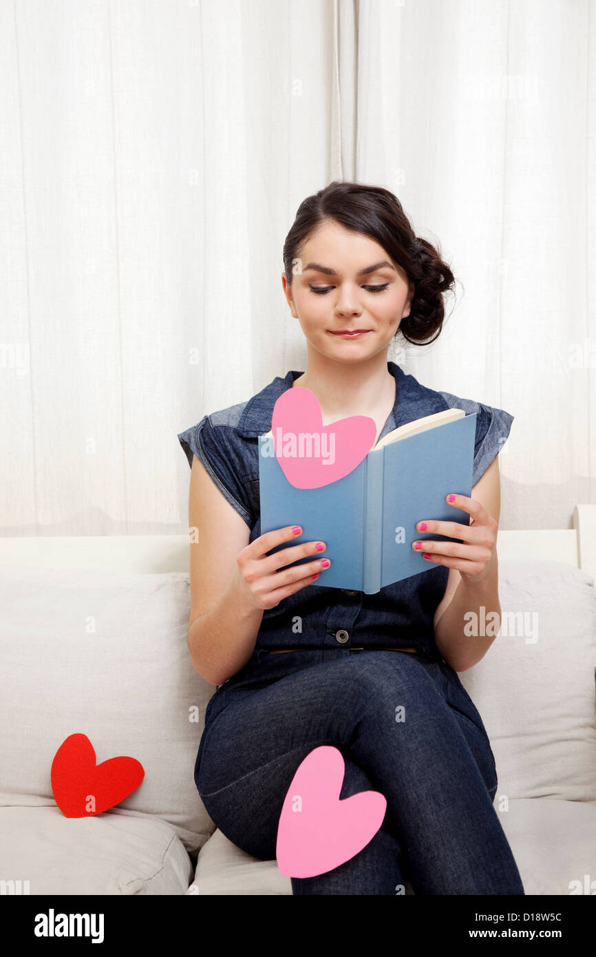 Young woman reading book with heart shapes Stock Photo
