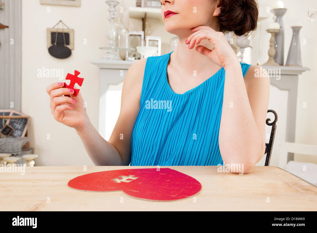 Woman doing heart shaped jigsaw puzzle holding piece Stock Photo