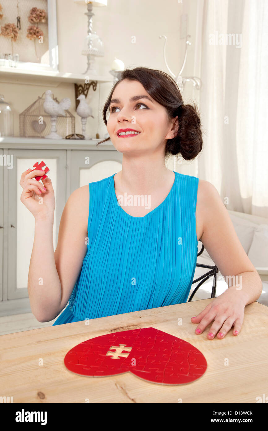 Woman doing heart shaped jigsaw puzzle holding piece Stock Photo