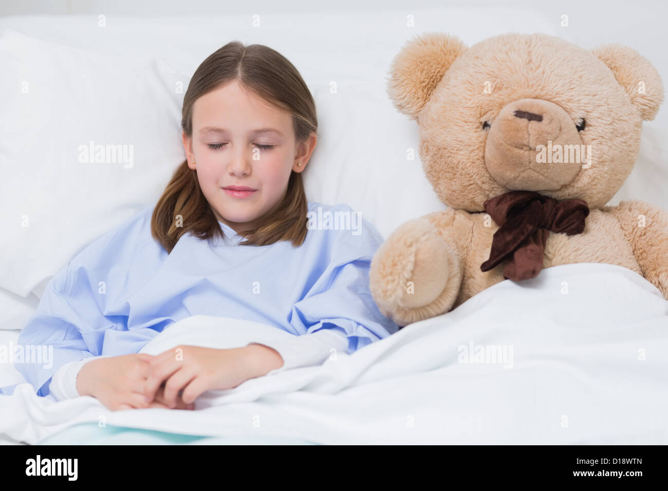 Child sleeping with a teddy bear while lying in a bed Stock Photo