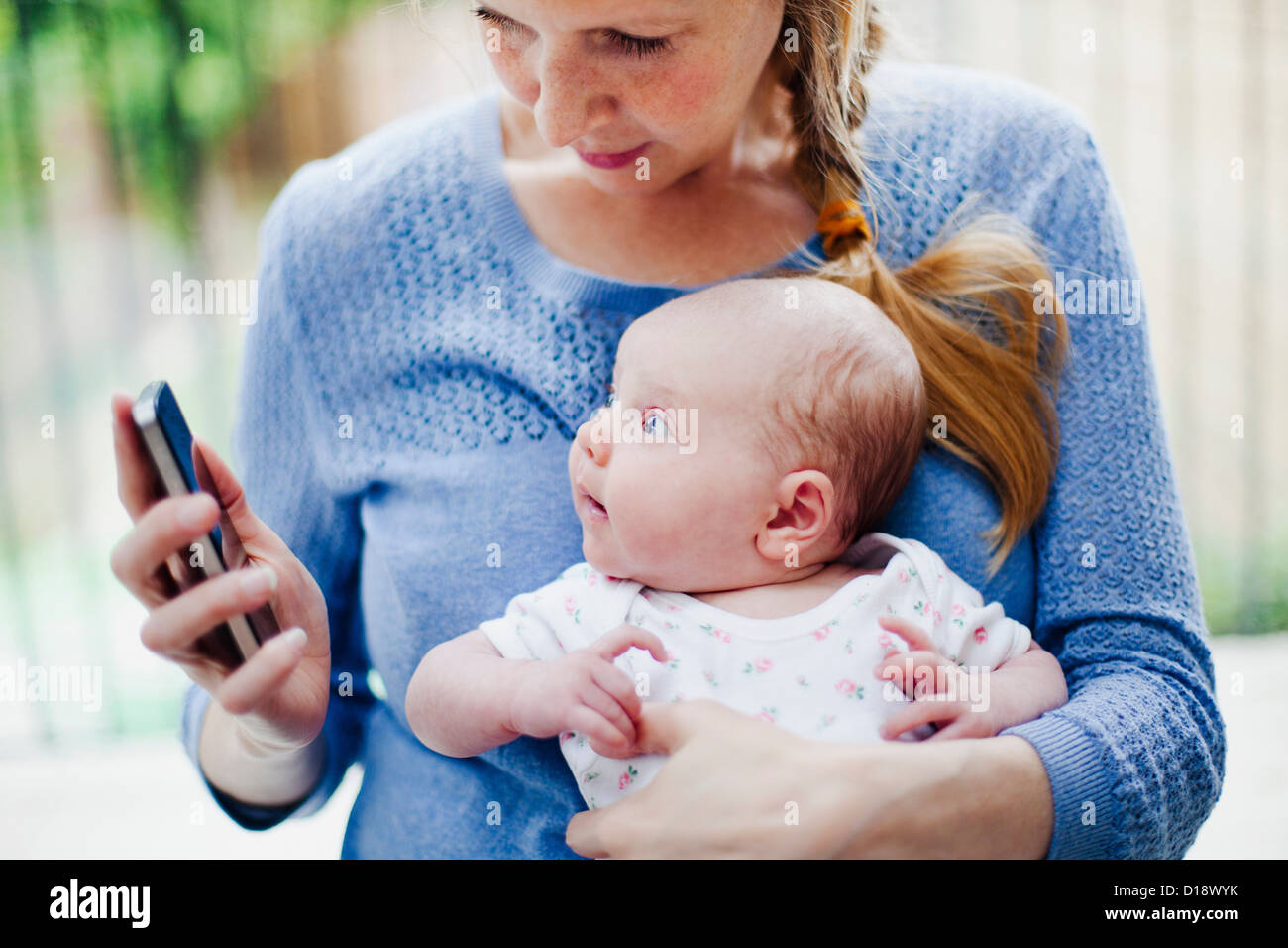Mother holding newborn daughter and cell phone Stock Photo Alamy