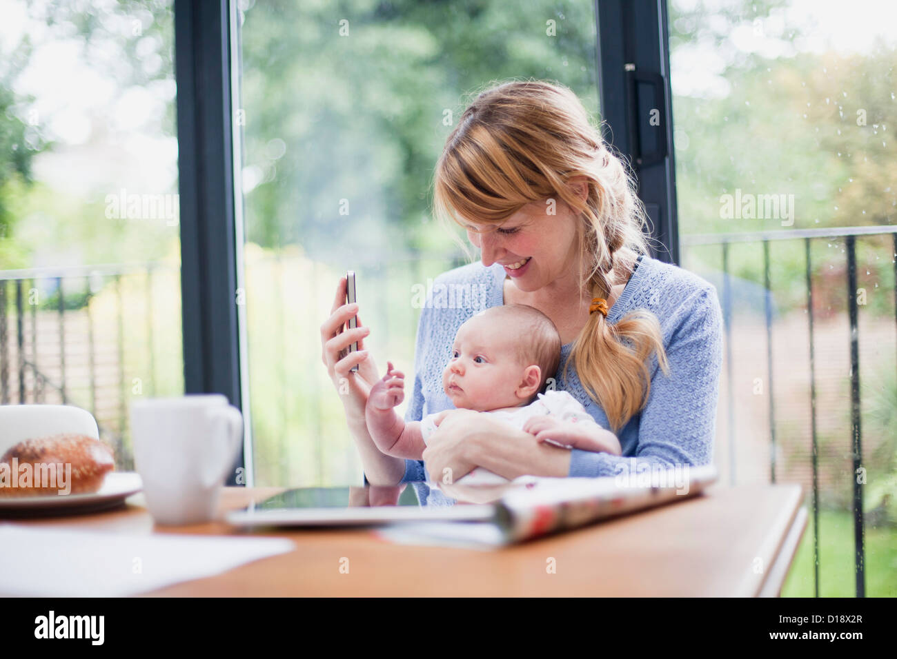 Mother with cell phone and newborn daughter Stock Photo Alamy