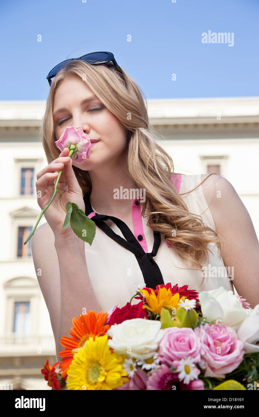 Young woman smelling rose from bouquet of flowers, eyes closed Stock ...