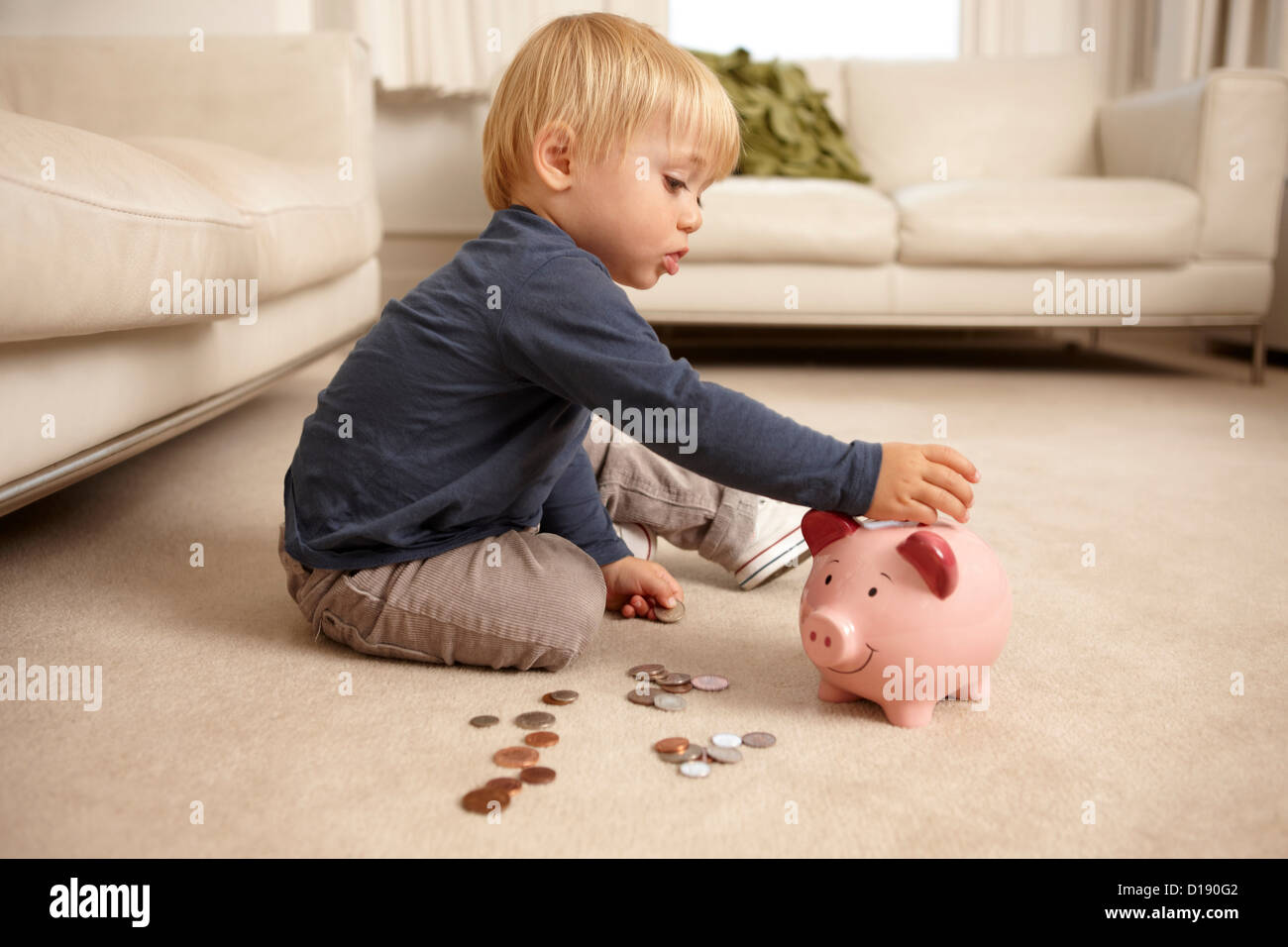 Boy putting coins in piggy bank Stock Photo - Alamy