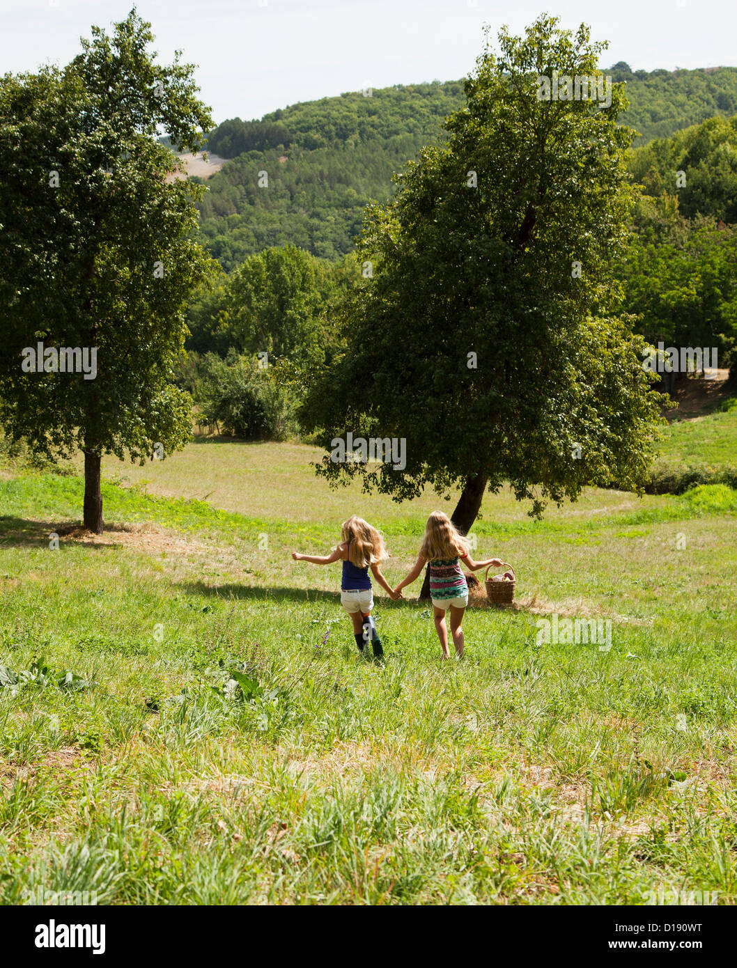 Two girls holding hands in field Stock Photo - Alamy