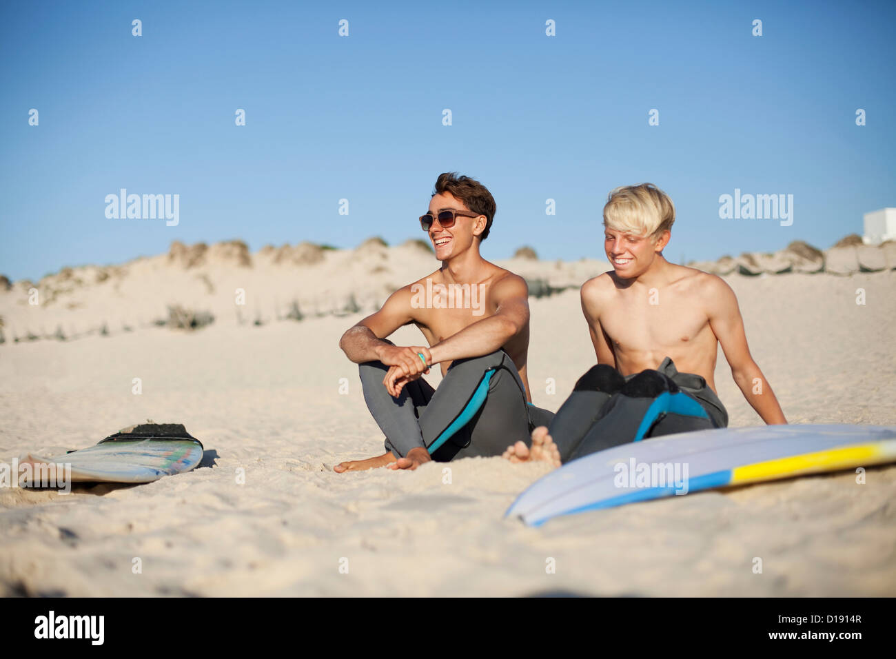 Two young surfers sitting on a beach Stock Photo