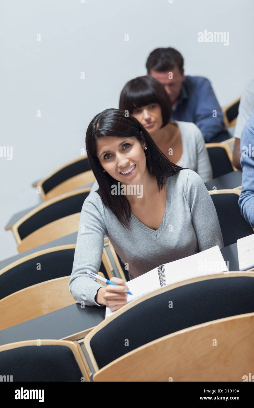 Smiling woman looking up from note taking Stock Photo - Alamy