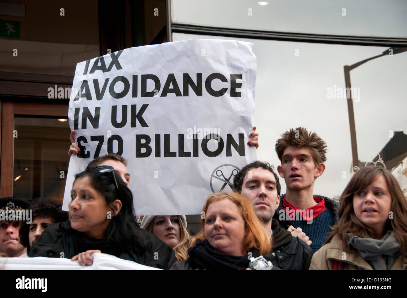 Protesters hold a sign saying Tax avoidance in the UK is £70 billion.UK Uncut flashmob demonstrate outside Starbucks . Stock Photo