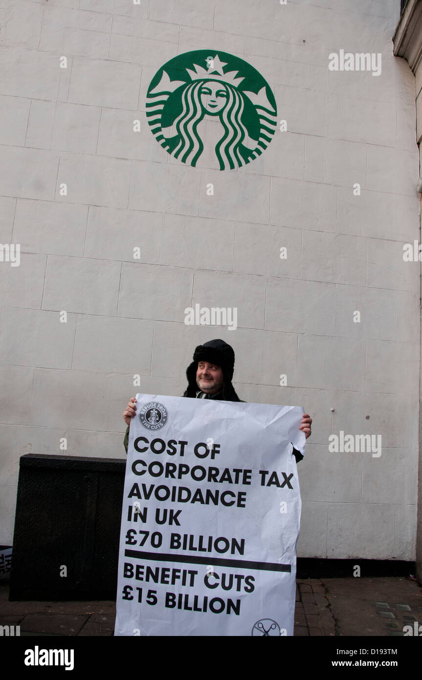 UK Uncut flashmob demonstrate in front of Starbucks .A protester holds a poster pointing out cost of Corporate tax avoidance Stock Photo