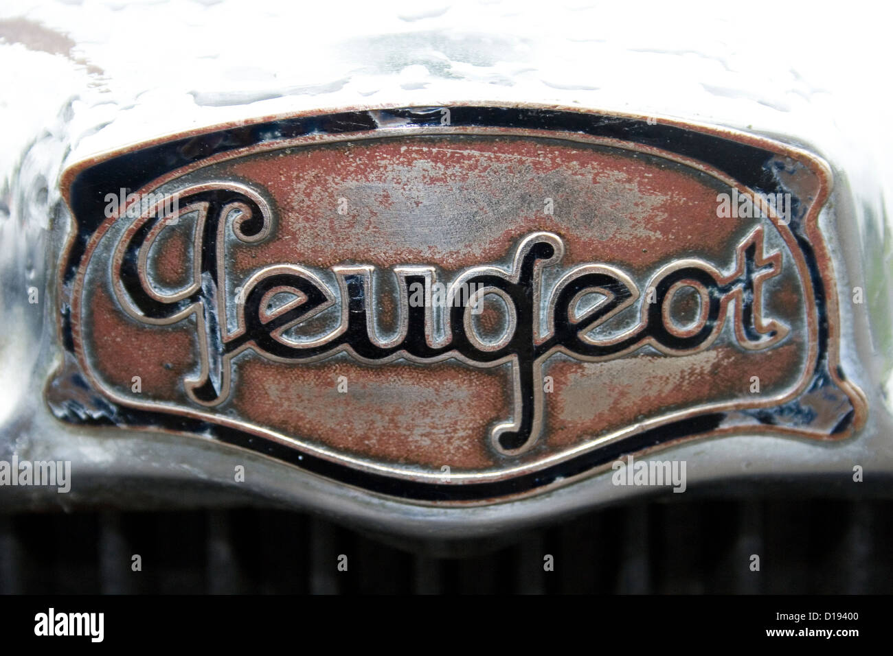 A vintage Peugeot badge on the front of an old Peugeot car at a car show. Stock Photo