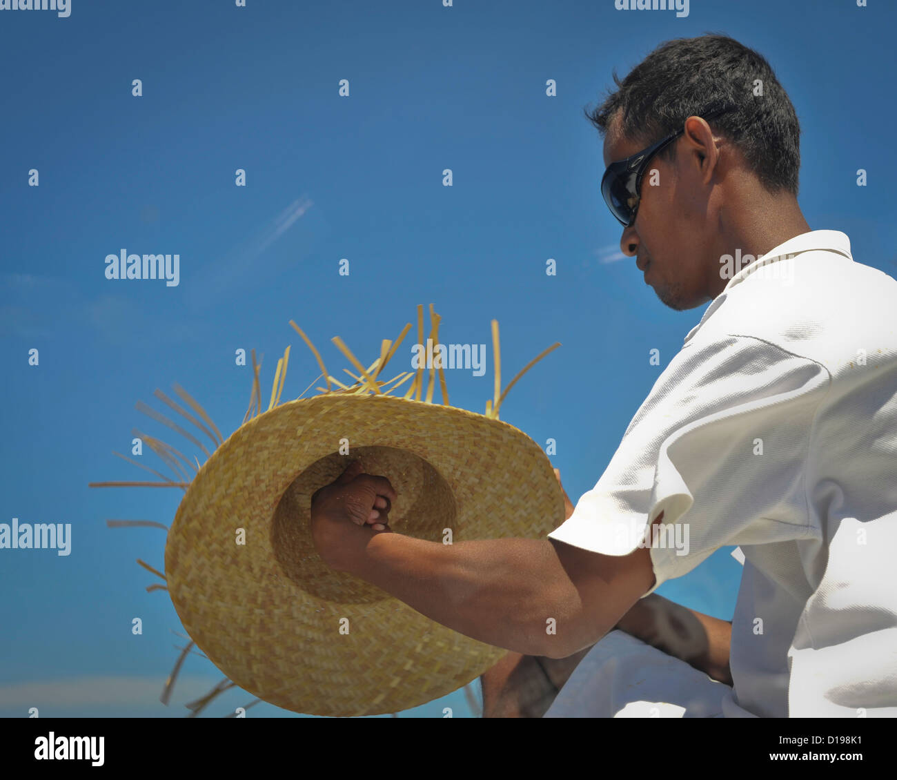 A crewman on an inter island ferry gets his hat ready to spin in the wind, Indonesia Stock Photo