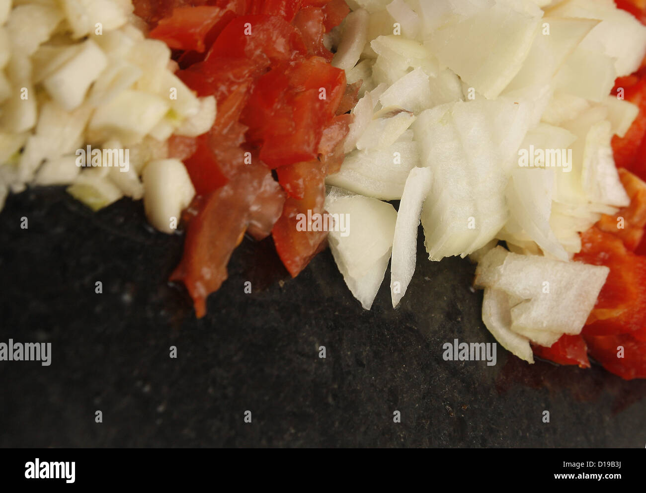 food pyramid of peppers, onions, tomatoes and garlic on marble chopping board Stock Photo