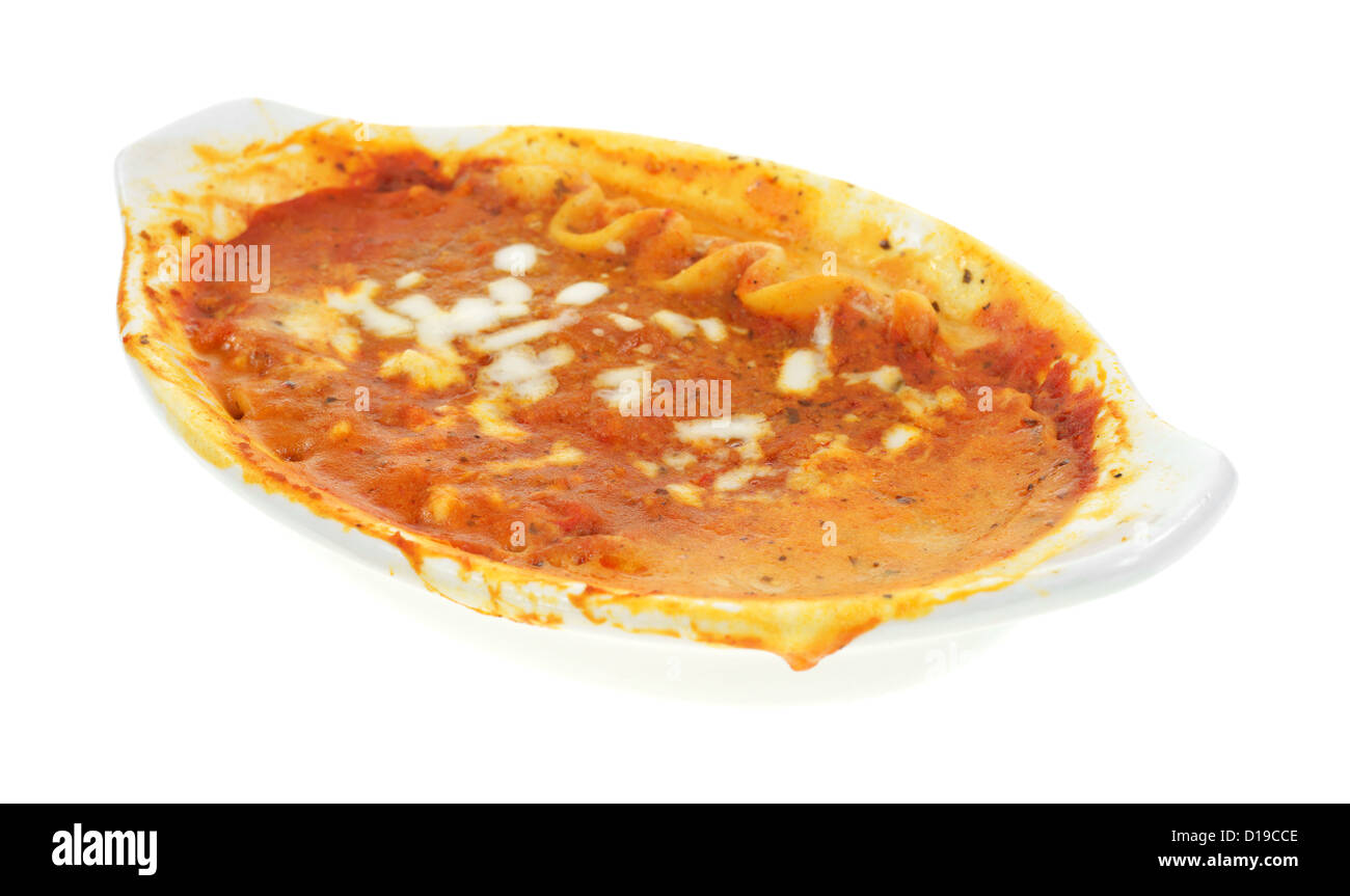 A lasagna tv dinner in a small baking dish that has been microwaved with tomato sauce spilling over the sides. Stock Photo