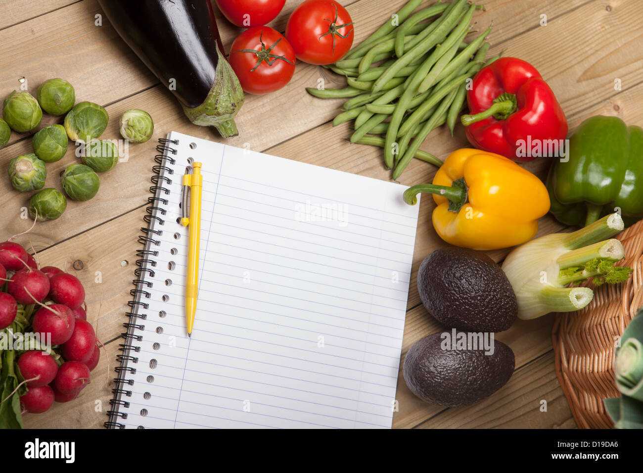 Vegetables with book and pen on wooden surface Stock Photo