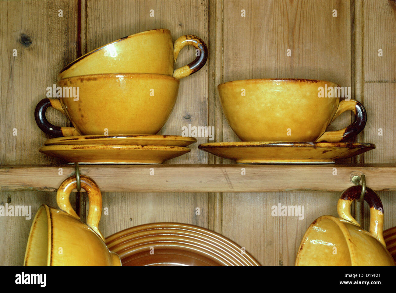 Yellow cups and saucers in cupboard Stock Photo Alamy