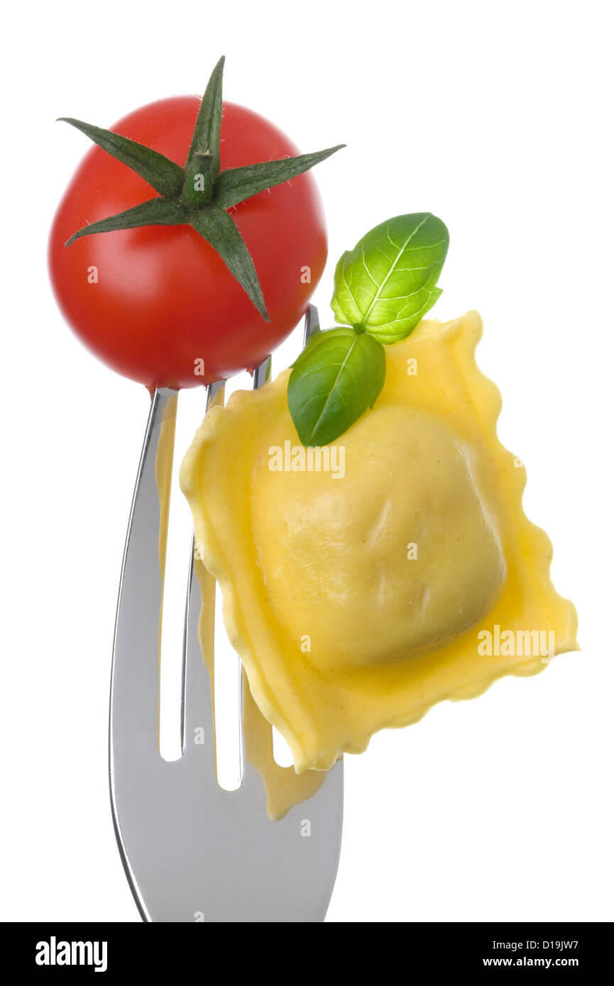 italian food ingredients ravioli pasta tomato and basil on a fork against white background Stock Photo