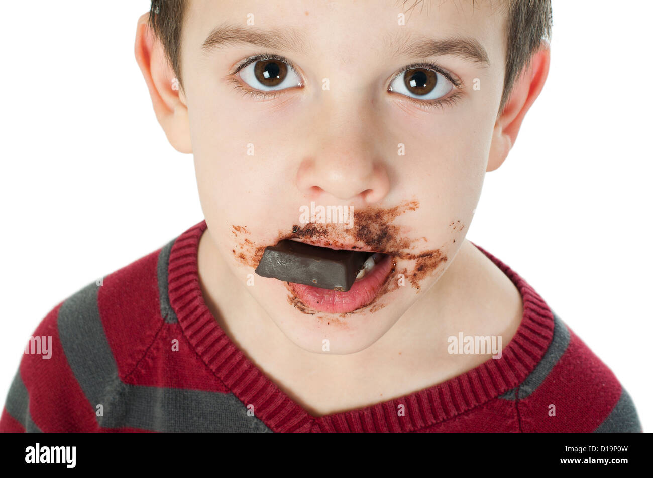 Smiling kid eating chocolate. Smeared stained with chocolate lips. White isolated Stock Photo