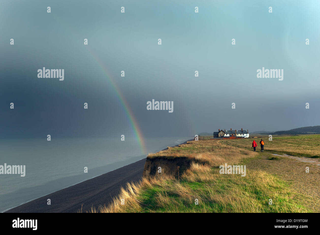 Rainbow over Coastal cottages Weybourne Norfolk in rain storm Stock Photo