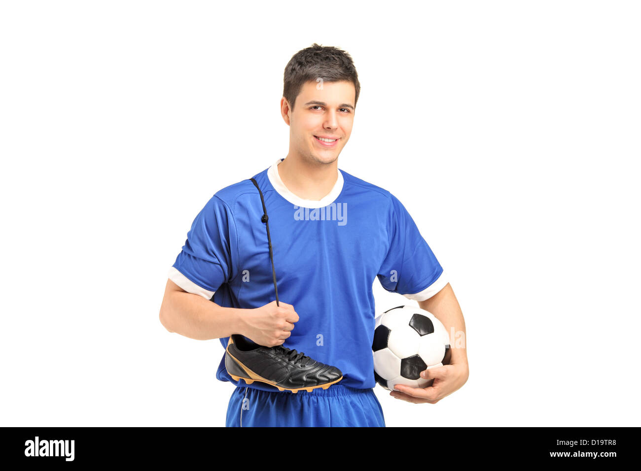 A smiling footballer in sport wear holding a soccer shoes and football isolated on white background Stock Photo