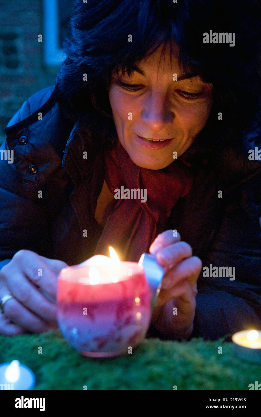 Woman lighting candles at an outdoor carol singing event at christmas time, Farnham, Surrey, UK. Stock Photo