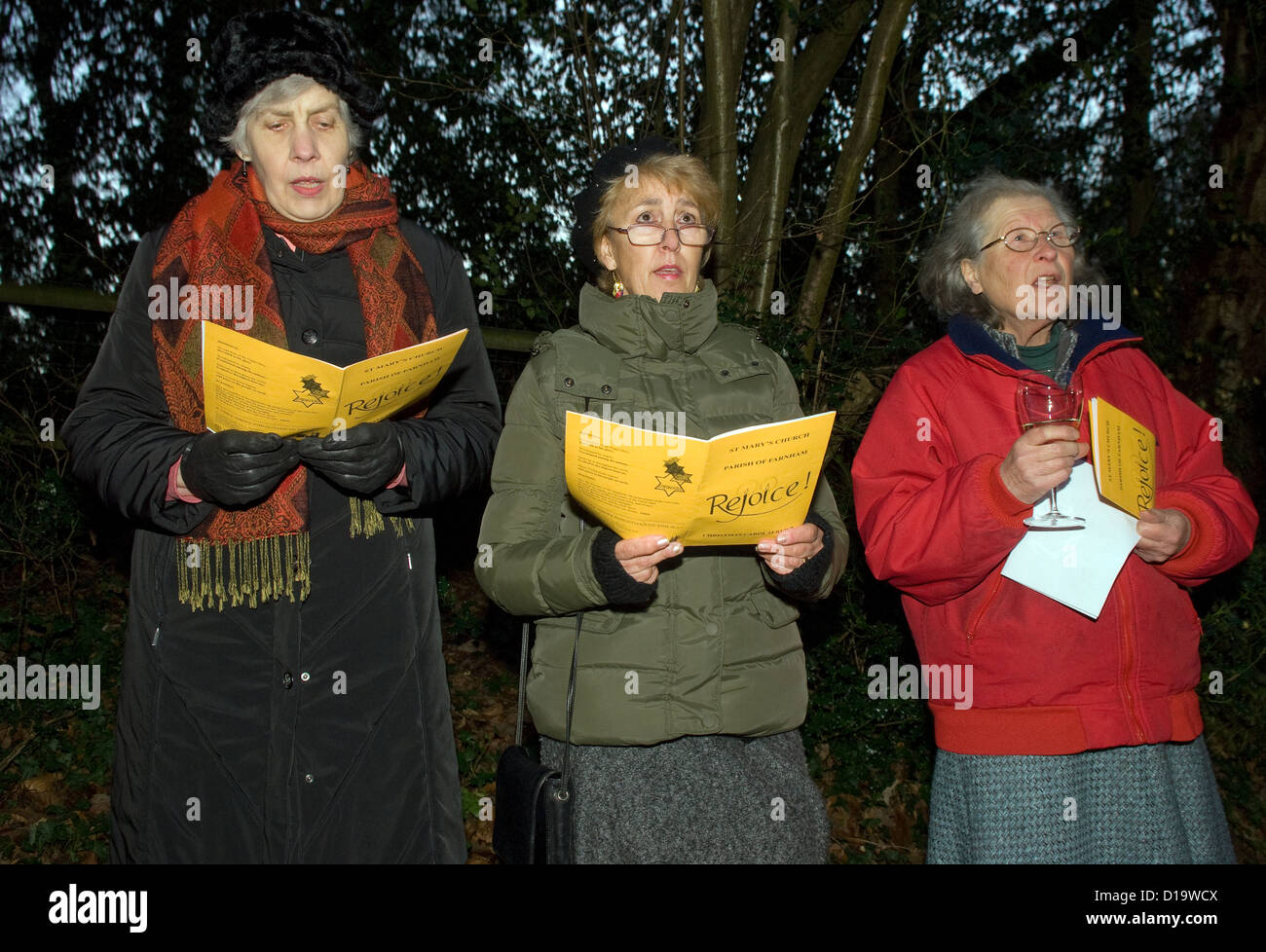 Local elderly residents singing at an evening outdoor carol service at christmas time, Farnham, Surrey, UK. Stock Photo