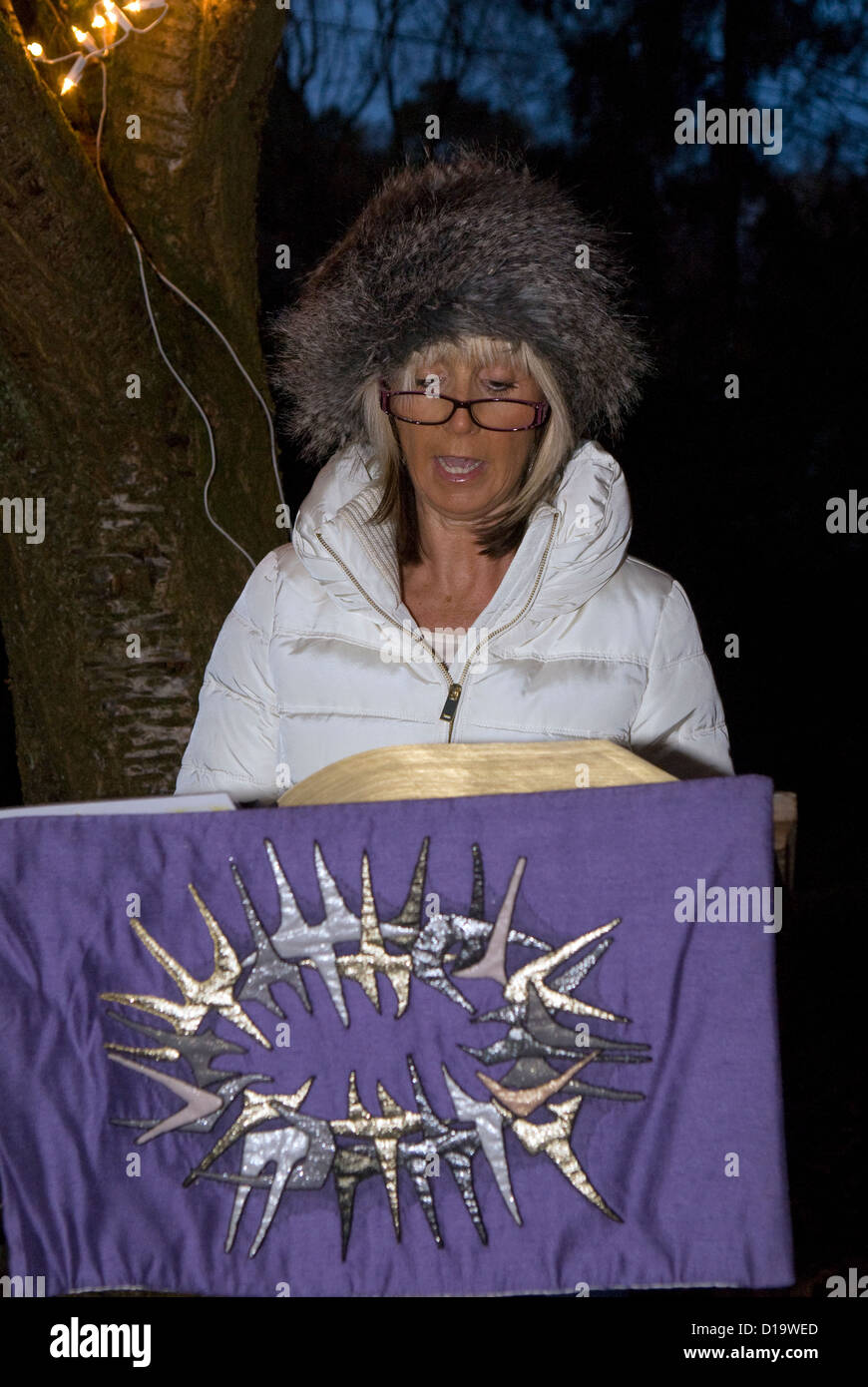 Local resident giving a bible reading at an evening outdoor carol service at christmas time, Farnham, Surrey, UK. Stock Photo