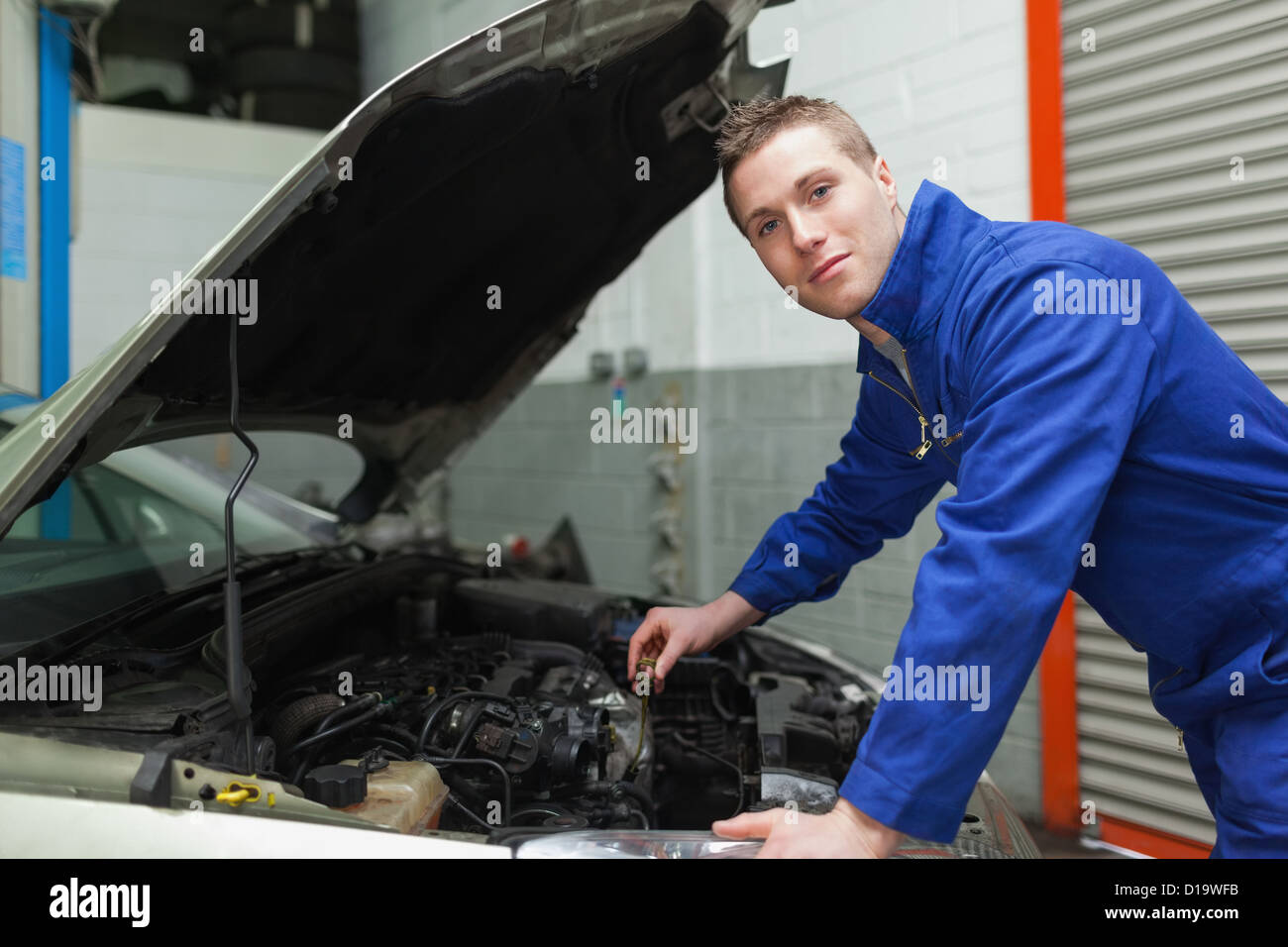 Confident mechanic checking car engine oil Stock Photo Alamy
