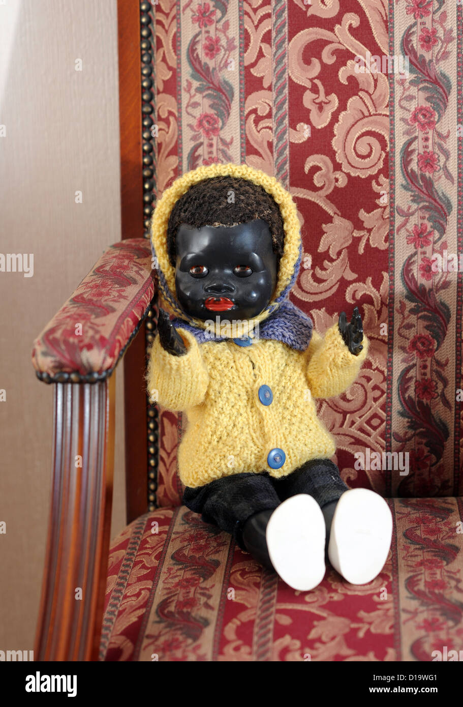 Antique black baby china toy doll in a chair Stock Photo