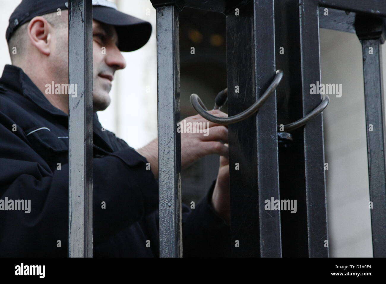 Sofia, Bulgaria; 12th December 2012. Police officer putting a chain on the gates in front of the Central Courthouse in Sofia to keep the about one hundred demonstrators away from the entrance. Credit:  Johann Brandstatter / Alamy Live News Stock Photo